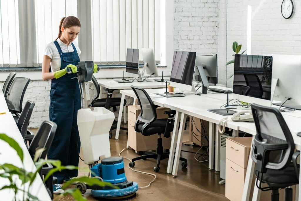 young cleaner washing floor in open space office with cleaning machine